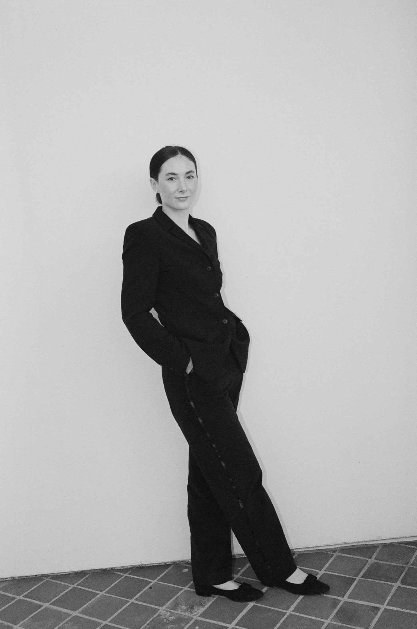Addison Hoffman, standing against a white wall in a black suit.